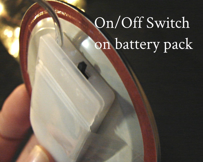 K&ouml;nnte beinhalten: Nahaufnahme eines wei&szlig;en Batteriefachs aus Kunststoff mit einem Ein-/Ausschalter. Der Schalter ist ein kleiner schwarzer Knopf.