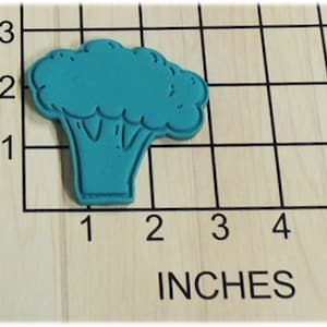 May include: A teal blue silicone cookie cutter shaped like a broccoli floret. The cutter is approximately 2 inches tall and 2 inches wide.