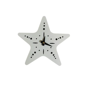 May include: A white starfish-shaped wall clock with black dots and lines marking the hours. The clock hands are black with a gold-colored center. The clock is a decorative item.