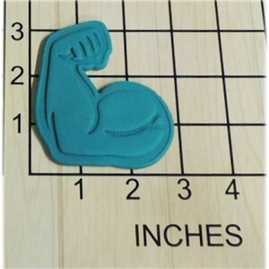 May include: A teal blue plastic cookie cutter shaped like a bicep flexing. The cookie cutter is 2 inches wide and 2 inches tall.