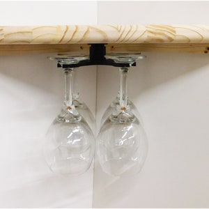 May include: A black metal wine glass rack mounted to a wooden shelf, holding four clear glass wine glasses.