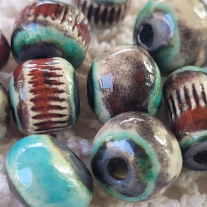 Peut inclure: Un ensemble de perles en céramique avec une variété de couleurs et de motifs. Les perles sont rondes et ont un trou au centre. Les couleurs incluent le brun, le blanc, le bleu et le vert.