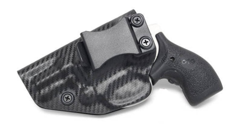 May include: A black and gray carbon fiber holster with a black handgun. The holster has a clip for attaching to a belt. The handgun has a textured grip.