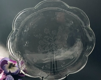 May include: A clear glass serving platter with a scalloped edge and an etched floral design.