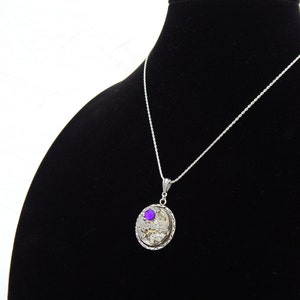 May include: A silver necklace with a round pendant featuring a purple gemstone and intricate clockwork details.