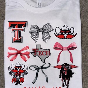 May include: White t-shirt with red and black Texas Tech University logos, including the school mascot, a red and black bow, and the words "Guns Up".