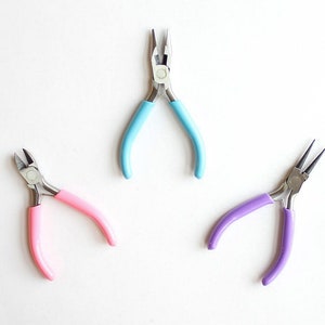May include: Three pairs of pliers with different colored handles: light blue, pink, and purple. The pliers are on a white background.