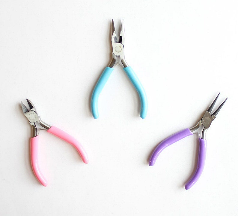May include: Three pairs of pliers with different colored handles: light blue, pink, and purple. The pliers are on a white background.