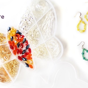 May include: A butterfly-shaped organizer filled with jewelry-making supplies, including gold and silver wires, beads, and earring hooks. Two pairs of beaded teardrop earrings in yellow and green are displayed. The word "fire" is visible.