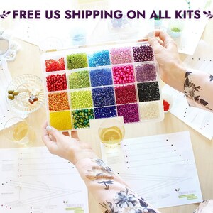 May include: A clear plastic container filled with 16 small compartments, each containing a different color of seed beads. The container is open and the beads are visible. The text "FREE US SHIPPING ON ALL KITS" is visible at the top of the image.