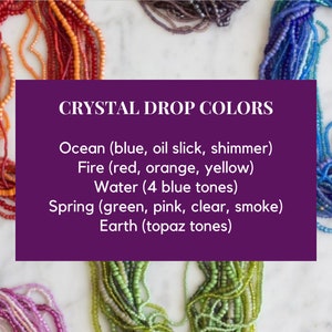May include: An assortment of crystal beads in various colors, including red, orange, blue, green, and pink. The image features text that reads "Crystal Drop Colors" and lists color categories such as "Ocean," "Fire," "Water," "Spring," and "Earth."