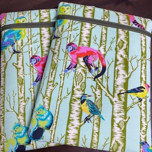May include: Two rectangular fabric pouches featuring a light blue background with a forest pattern of green birch trees. The print includes colorful illustrations of monkeys, owls, squirrels, and various birds, finished with a dark olive green zipper.