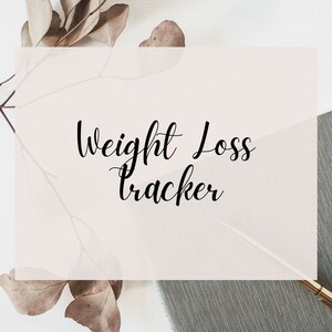Puede incluir: Un cuaderno gris con el texto "Weight Loss Tracker" escrito en cursiva negra sobre un fondo rosa. El cuaderno está rodeado de hojas secas.