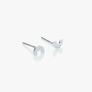 Op de afbeelding: Een paar zilveren oorbel studs met een halve cirkel ontwerp. De oorbellen zijn eenvoudig en minimalistisch.