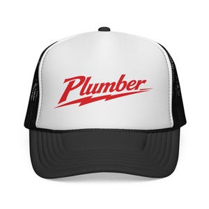 Puede incluir: Gorra de camionero en blanco y negro con la palabra "Plumber" en rojo en la parte delantera. La palabra está subrayada con un rayo rojo. La gorra tiene una visera negra y una parte trasera de malla.
