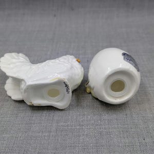 Puede incluir: Un juego de salero y pimentero de cer&aacute;mica blanca. Uno tiene forma de p&aacute;jaro con alas detalladas, el otro tiene forma de huevo. Ambos tienen agujeros para dispensar y est&aacute;n marcados "JAPAN".