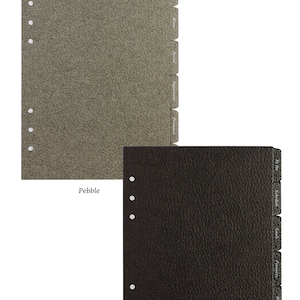 May include: Two sets of 6-tab leather card dividers for planners, one in pebble gray and one in black. Each divider features six punched holes along the left edge and six labeled tabs on the right side. The text reads: Optional add-on: 6-Tab Leather Card Dividers with customisable sticker tab labels.
