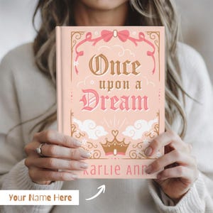May include: A hardcover book with a light pink cover featuring the title "Once upon a Dream" in gold and pink lettering. The cover design includes decorative elements like bows, clouds, and a crown. The author's name, "Karlie Ann," is printed at the bottom.