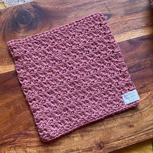 May include: A pink crocheted dishcloth or kitchen towel with a tag that says "Handmade in the USA with love".