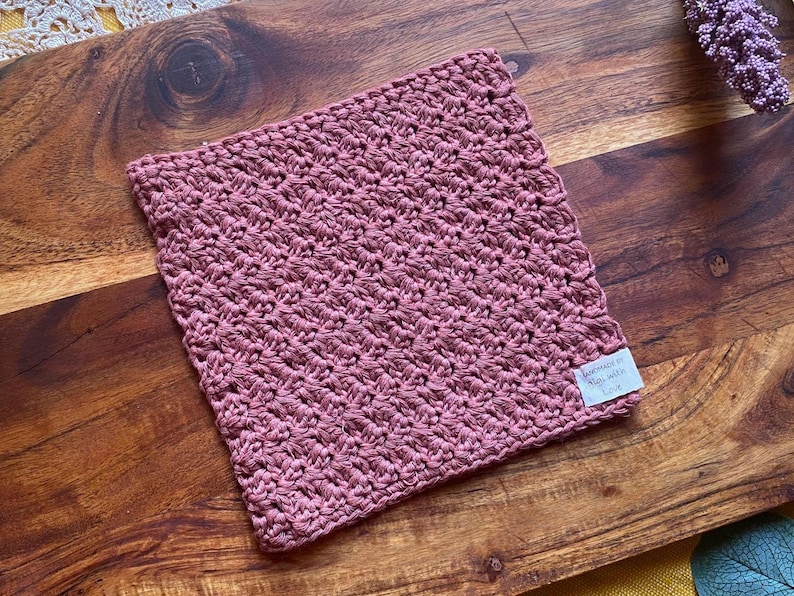 May include: A pink crocheted dishcloth or kitchen towel with a tag that says "Handmade in the USA with love".