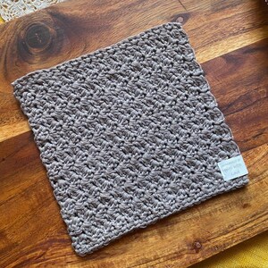 May include: A gray crocheted dishcloth with a white tag that says "Handmade in South Africa".
