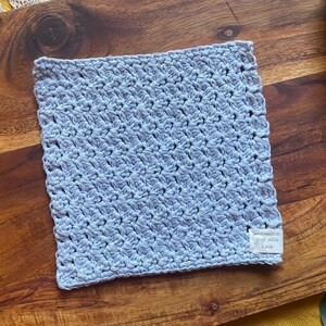 May include: A light blue crocheted dishcloth with a white tag that reads "Handmade with Love".