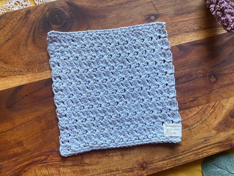 May include: A light blue crocheted dishcloth with a white tag that reads "Handmade with Love".