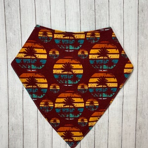 May include: A maroon bandana with a repeating pattern of palm trees and sunset stripes in shades of yellow, orange, blue, and green.