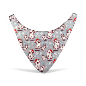 May include: A gray bandana featuring a repeating pattern of cartoon ghosts wearing Santa hats and reindeer with snowflakes. The bandana is shaped like a triangle with rounded edges, suitable for pets.