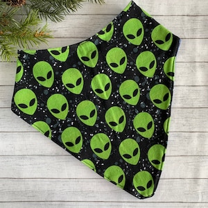 May include: A black bandana with a green alien pattern. The aliens have large eyes and are repeated throughout the bandana.