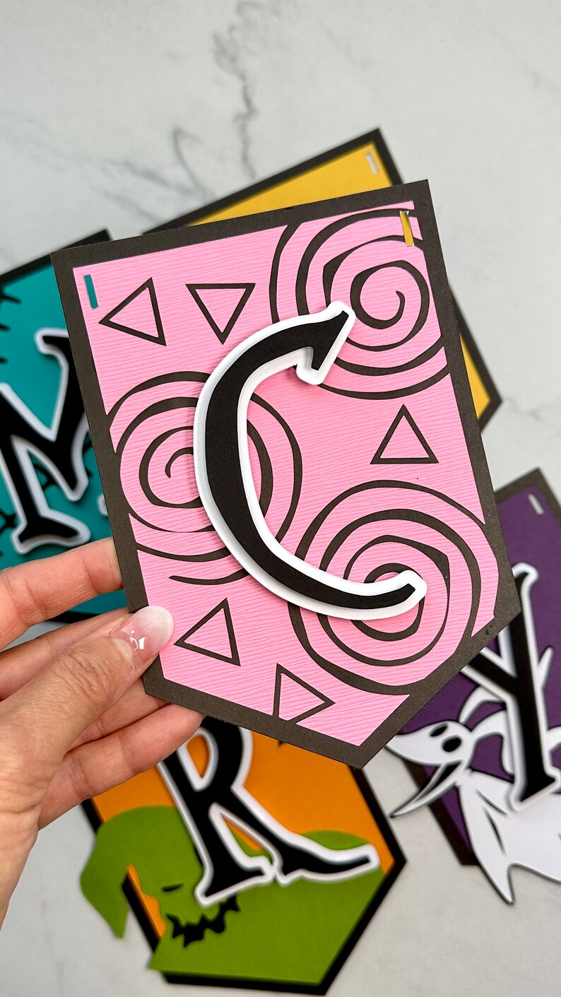 Puede incluir: Una pancarta de papel rosa y negro con la letra "C" en blanco y negro. La pancarta tiene un patr&oacute;n de espiral y tri&aacute;ngulos rosas.