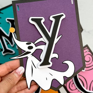 Puede incluir: Pancarta morada con la letra Y en blanco y negro, un personaje fantasma blanco con ojos negros y una bola amarilla en la nariz, y un borde negro.