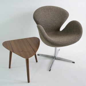 May include: A brown, triangular side table with three legs sits next to a gray, upholstered swivel chair with a chrome base.