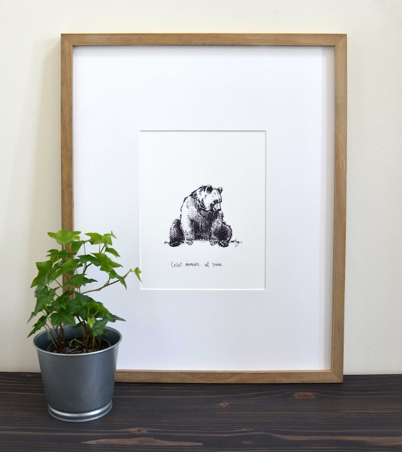 May include: A framed black and white ink drawing of a bear sitting down. The drawing is titled "Coolest moments are silent".