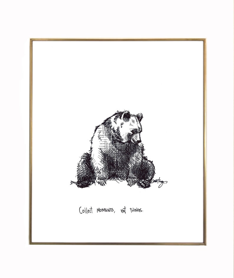 May include: Black and white line drawing of a bear sitting down with the text "Collect moments, not things." below it.