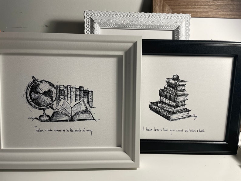 May include: Two framed black and white ink drawings. The first drawing depicts a globe, a stack of books, and an open book with the text "Teachers create tomorrows in the minds of today." The second drawing depicts a stack of books with an apple on top and the text "A teacher takes a hand, opens a mind and touches a heart."