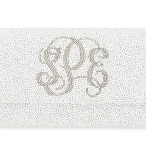 May include: White beaded clutch with a silver monogram of the letters "SPE".