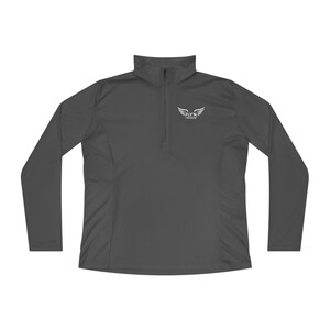 May include: A dark grey long-sleeved athletic top with a quarter-zip neckline. The top features the white text "FLY'N TRAINING" with a wing logo on the upper chest. The material appears to be a lightweight, breathable fabric.