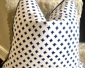 May include: A white pillow with a navy blue diamond pattern. The pillow has a navy blue trim around the edges.