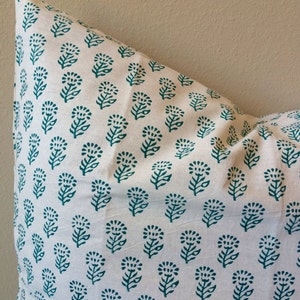 May include: A white pillowcase with a teal floral pattern. The pattern is a repeating design of small flowers with leaves.