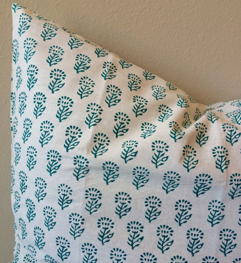 May include: A white pillowcase with a teal floral pattern. The pattern is a repeating design of small flowers with leaves.