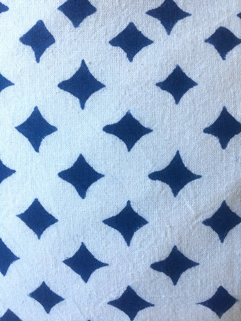 May include: White fabric with a repeating pattern of dark blue diamond shapes.
