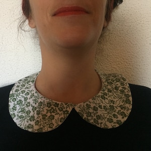 Peut inclure: Un col claudine blanc avec un motif floral vert.