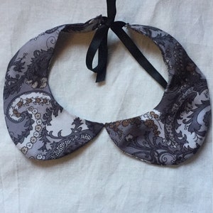Peut inclure: Un col en tissu &agrave; motif paisley gris et marron avec un ruban noir.