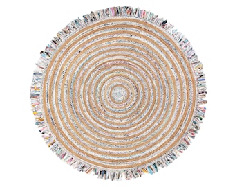 Op de afbeelding: Rond jute vloerkleed met concentrische cirkels in natuurlijke en witte tinten. Het kleed heeft een gefranjerde rand met kleurrijke stoffen accenten. Een decoratieve vloerbedekking voor woonkamers, slaapkamers of entrees.