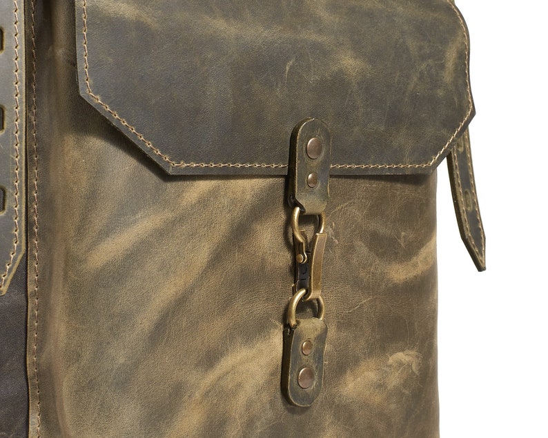 Op de afbeelding: Een bruine leren schoudertas met een klep sluiting en een messing gesp. De tas heeft een verweerde look en is gemaakt van hoogwaardig leer.