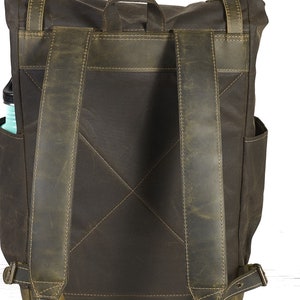 Op de afbeelding: Een bruine leren rugzak met verstelbare schouderbanden. De rugzak heeft een groot hoofdvak en een kleiner vak aan de voorkant.