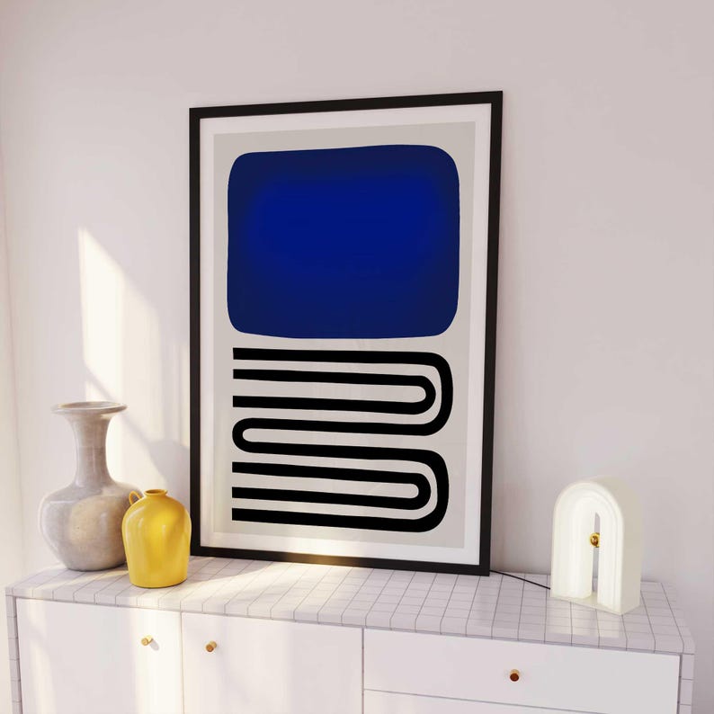 May include: A framed wall art print featuring a large solid dark blue rectangle positioned above a series of three stacked black horizontal U-shaped lines, all set against a light gray background within a thin black frame.