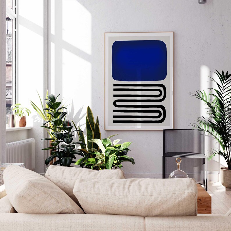 May include: A framed wall art print featuring a solid dark blue rectangle positioned above a series of black horizontal lines that form a repeating, rounded, serpentine pattern on a light gray background, displayed in a bright room.