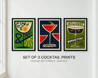 Op de afbeelding: Een set van drie ingelijste kunstprints met gestileerde cocktailillustraties. De linker print toont een groene Gin Tonic, de middelste print een rode Cosmopolitan en de rechter print een groene Espresso Martini met koffiebonen.